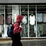 Un hombre pasea frente a una tienda de ropa en la capital en un día de lluvia y bajada de temperaturas