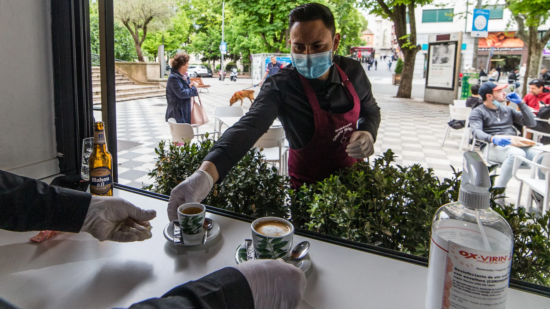 Un camarero coge varios cafés para servirlos en la terraza de un bar abierto en la Plaza de la Hispanidad de Cuenc