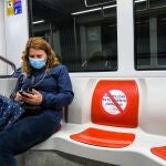 Una mujer, que hace un viaje en el metro de Sevilla, guarda la distancia de seguridad obligatoria en el transporte público