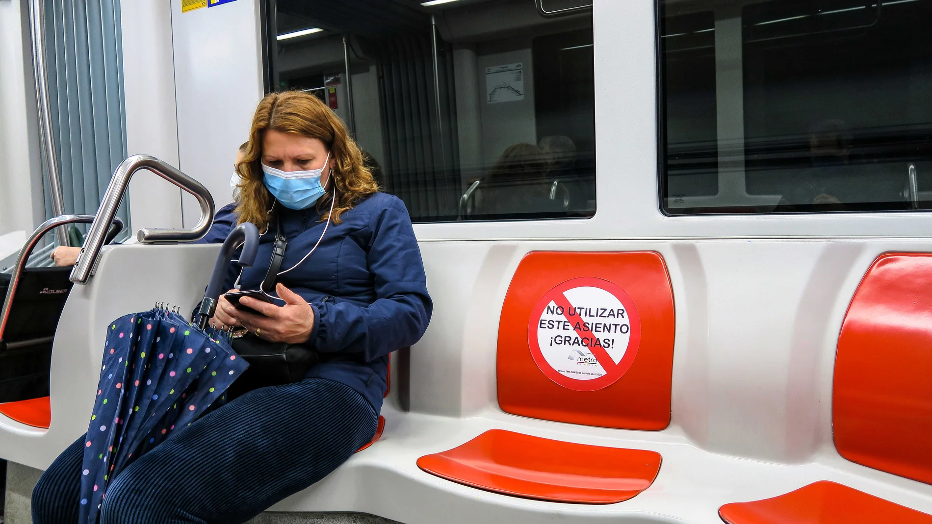 Una mujer, que hace un viaje en el metro de Sevilla, guarda la distancia de seguridad obligatoria en el transporte público