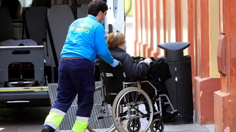Un sanitario lleva a una anciana a la residencia dónde está alojada