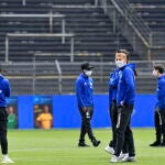 Los jugadores del Schalke inspeccionan el césped con mascarilla antes del partido