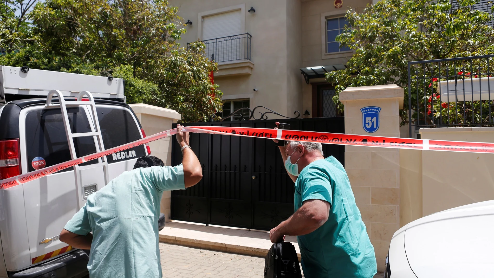 Doctor Chen Kugel, head of Israel National Center of Forensic Medicine and his colleague, pass through a police cordon as they enter China's ambassador to Israel, Du Wei's house in Herzliya, near Tel Aviv, Israel
