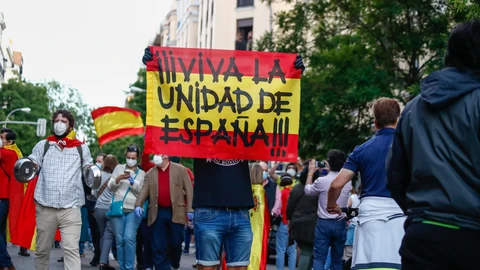 Un hombre sostiene una bandera de España durante una manifestación frente a la sede del PSOE en Madrid