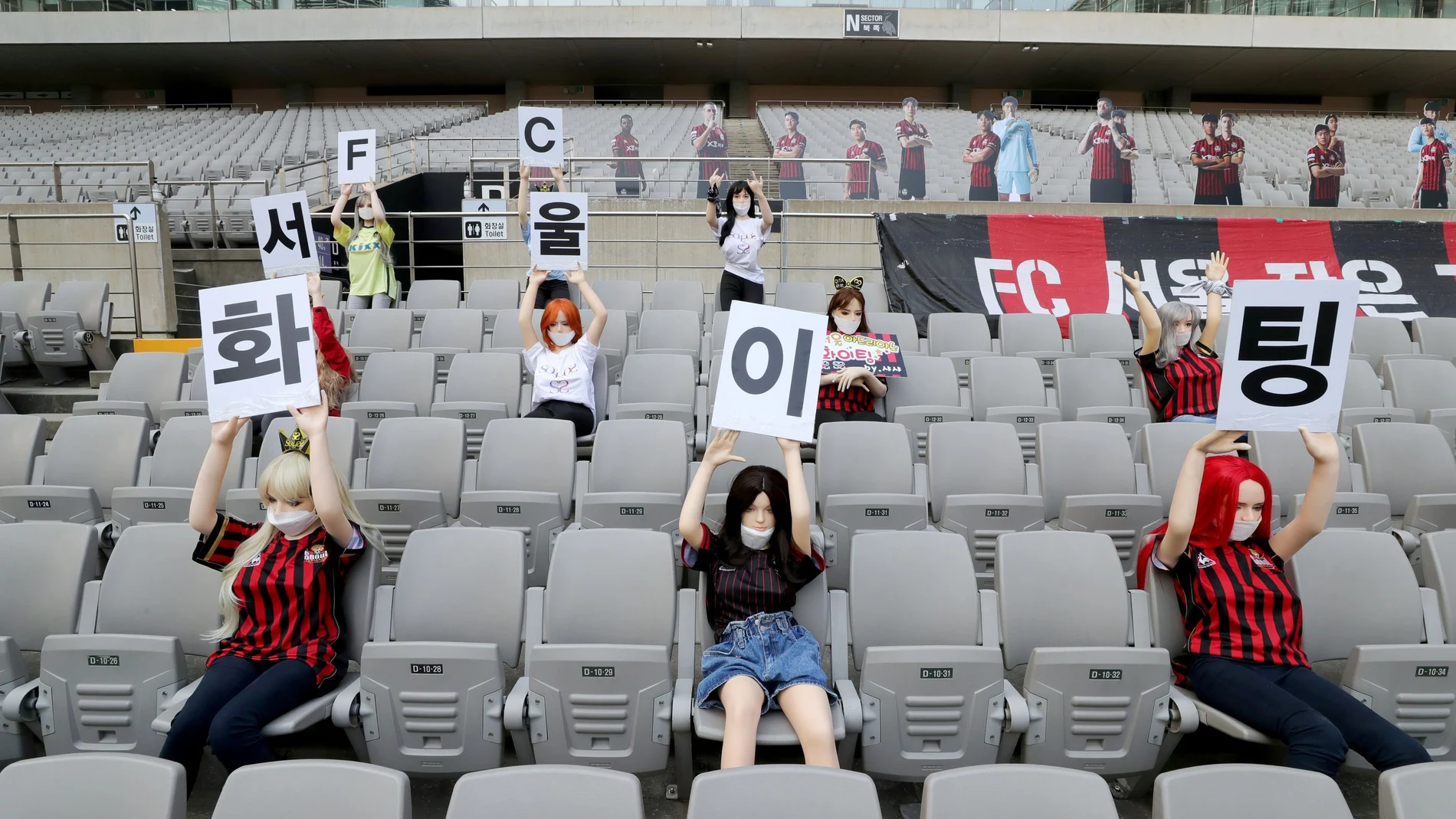 Mannequins are placed in spectator seats to cheer during football match in Seoul