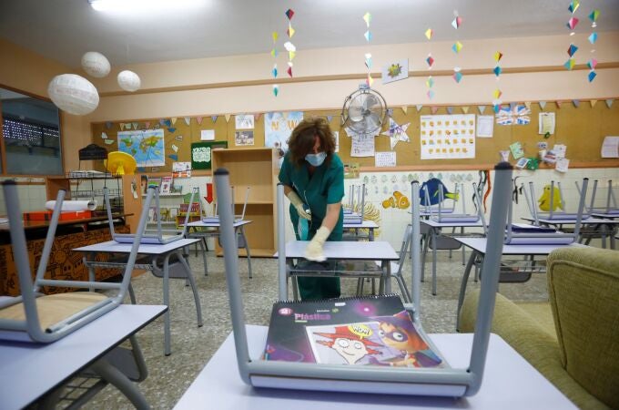 Una limpiadora desinfecta el mobiliario del colegio Cervantes de Córdoba