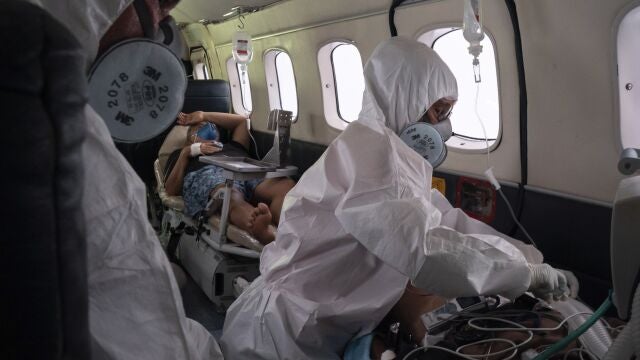 Doctor Daniel Siqueira, left, and nurse Janete Vieira monitor COVID-19 patients AbraÃ£o Lasmar, left, and Sildomar Castelo Branco onboard an aircraft as they are transferred from Santo AntÃ´nio do IÃ§a to a hospital in Manaus, in Brazil's Amazon state, Tuesday, May 19, 2020. (AP Photo/Felipe Dana)