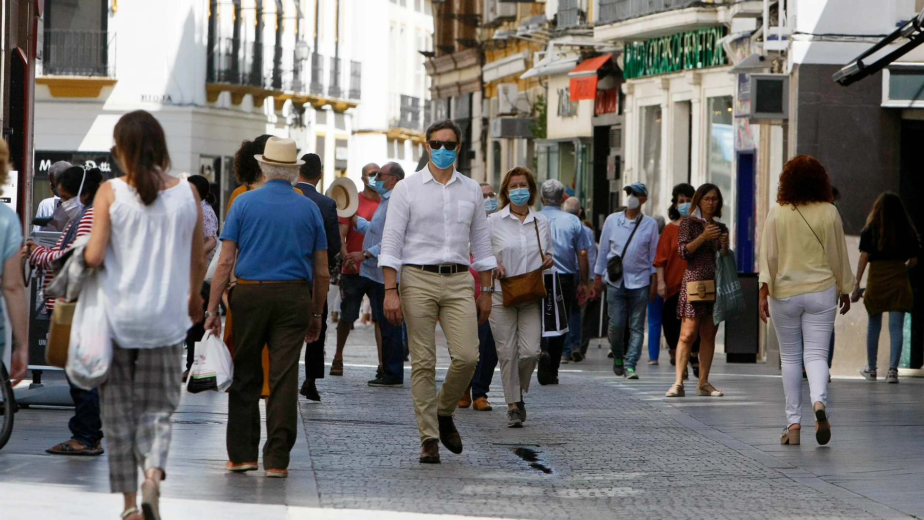 Sevillanos paseando por el centro, ayer, primer día de uso obligatorio de las mascarillas
