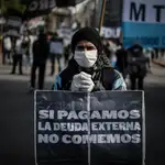 Un hombre con una mascarilla se manifiesta contra el pago de la deuda externa, en Buenos Aires