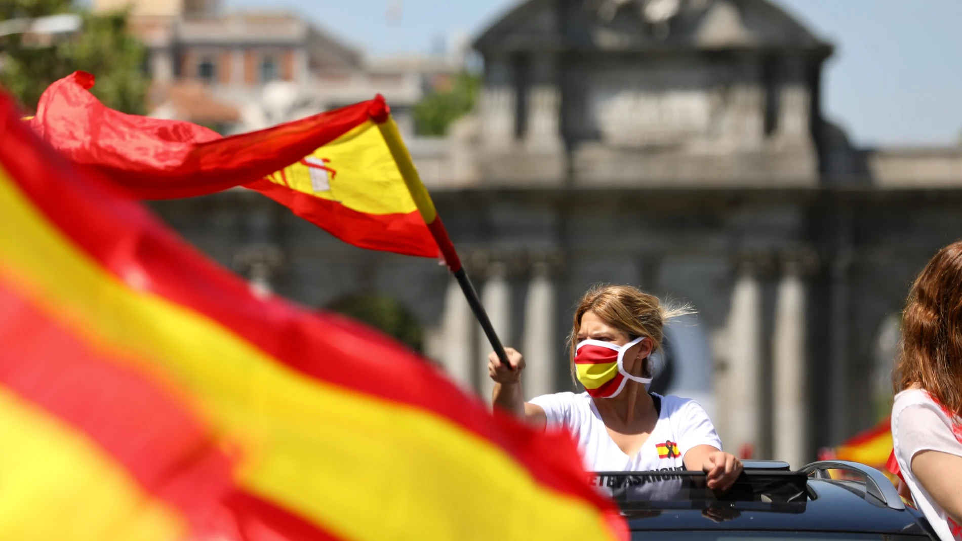Coches y motos, con pancartas y banderas de España, circulan por las calles de la capital en la manifestación de Vox para pedir la dimisión del Gobierno de Pedro Sánchez por su gestión durante la pandemia del Covid-19.