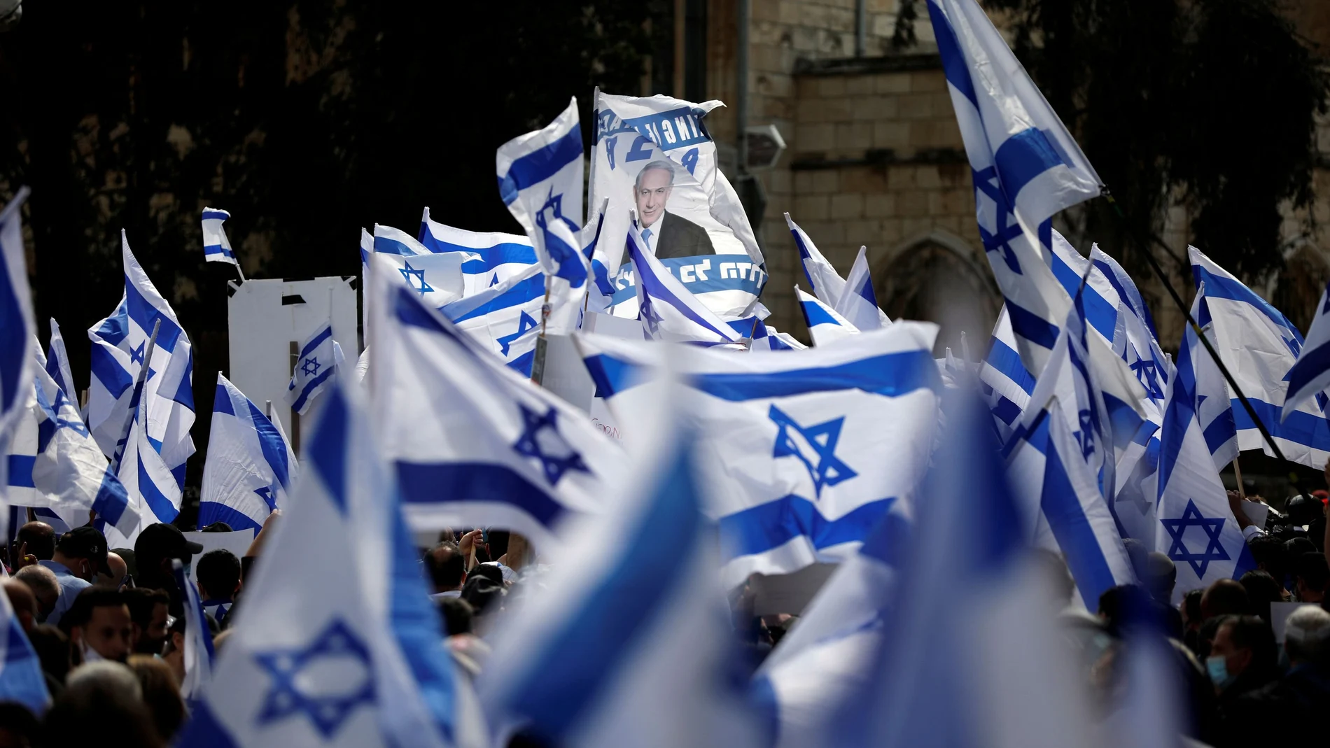 Supporters of Israeli Prime Minister Benjamin Netanyahu wave Israeli flags during a rally as Netanyahu's corruption trial opens, near the Jerusalem District Court