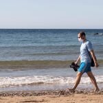 Un hombre con mascarilla camina por la playa