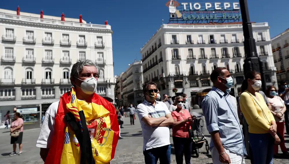 Varios ciudadanos se congregan a las puertas de la sede de la Presidencia de la Comunidad de Madrid para guardar un minuto de silencio