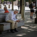 Un hombre con mascarilla lee el periódico en Sevilla, que está en fase 2