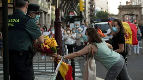 Participantes en una protesta del pasado sábado por las calles de Zaragoza ofrecen un ramo de flores a dos miembros de la Guardia Civil