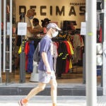 Un hombre protegido con mascarilla pasa junto a una tienda de deportes en Madrid