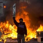 Un manifestante sostiene un monopatín en medio de las llamas durante una protesta en Los Ángeles