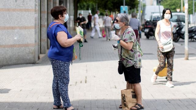 Dos mujeres mantienen la distancia social mientras hablan en una calle de Barcelona este martes