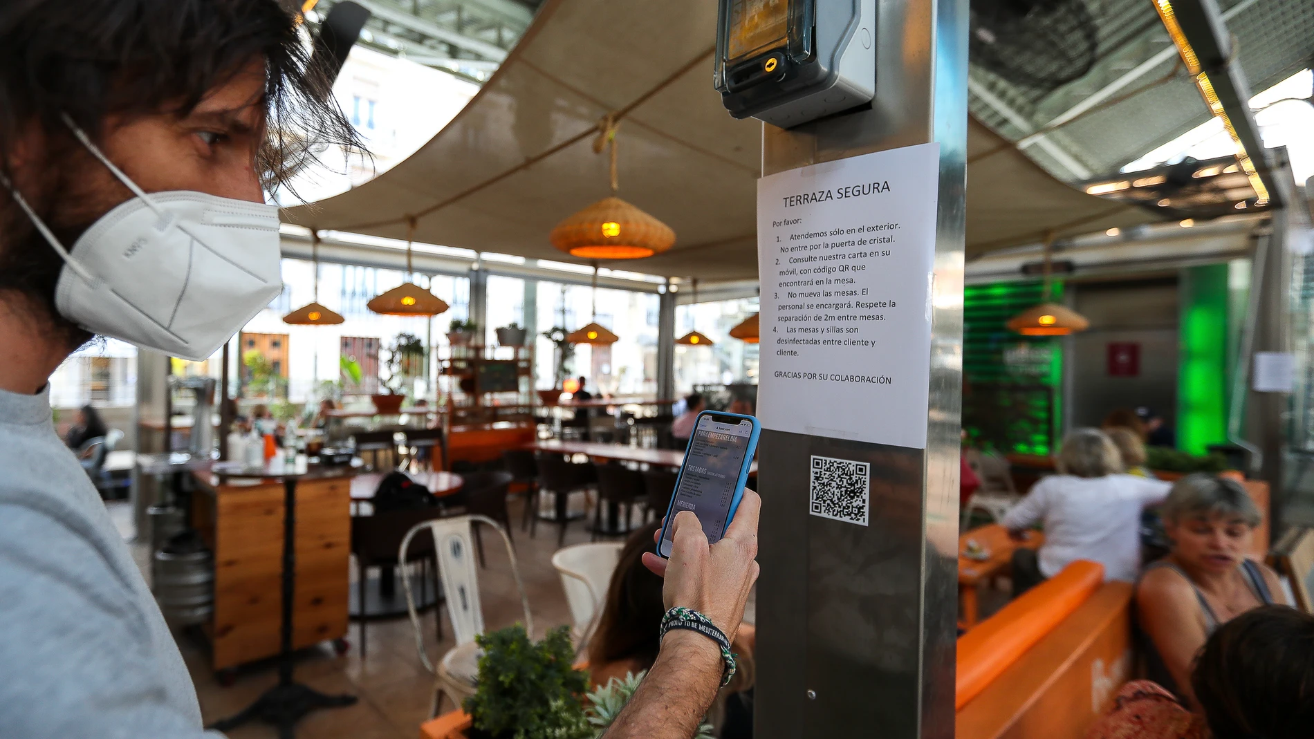 Una persona consulta la carta de productos con código QR en un bar de el Mercado de Colón