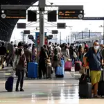 Viajero protegidos con mascarilla esperan en los andenes de la estación central de Milán