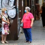 Imagen de archivo de dos mujeres manteniendo la distancia de seguridad y utilizando mascarillas en la calle