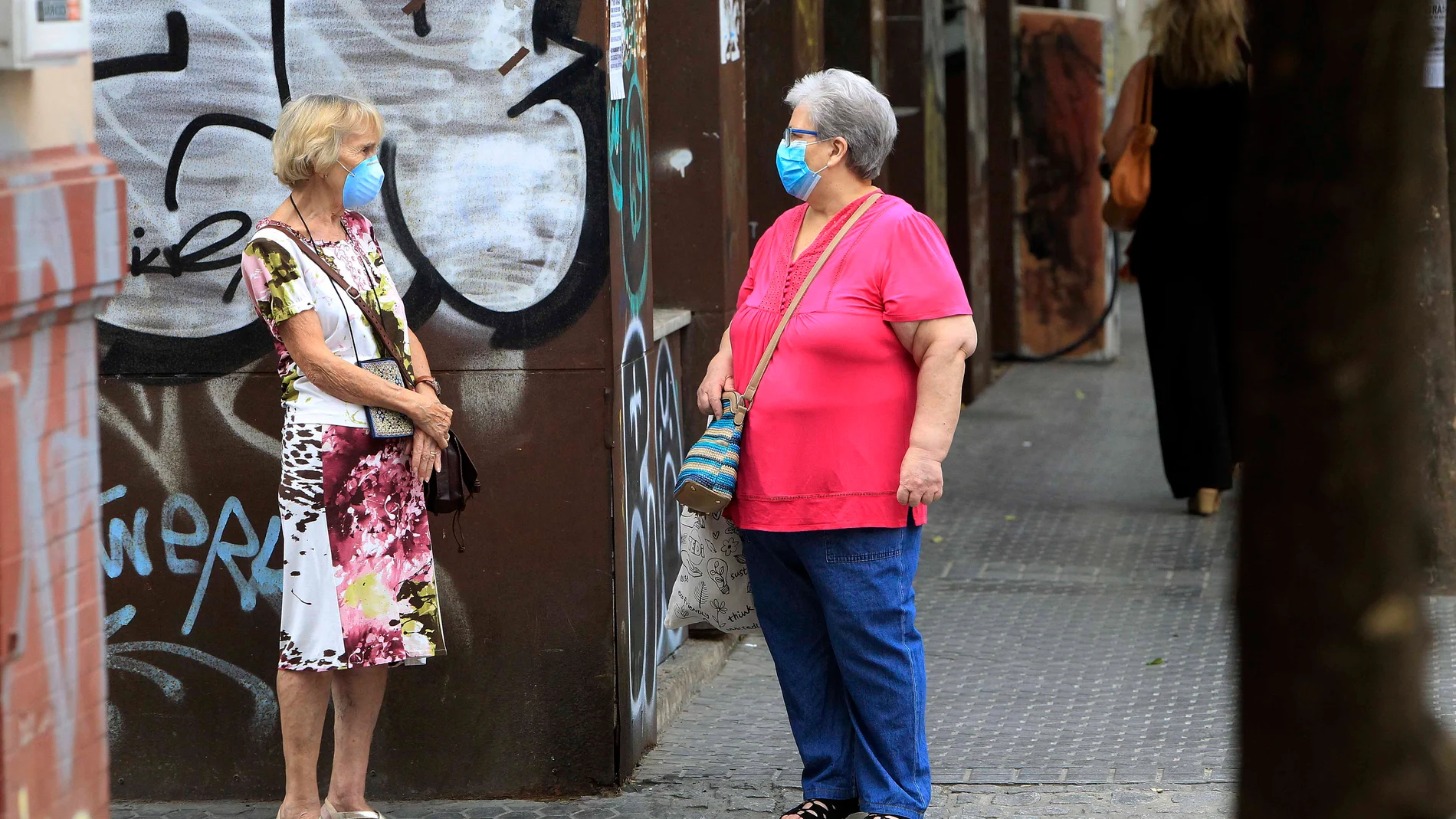 Imagen de archivo de dos mujeres manteniendo la distancia de seguridad y utilizando mascarillas en la calle