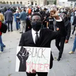 Malcom Biiga, un funcionario de 26 años, posa junto a un cartel contra la violencia policial en una manifestación en los aledaños de la Embajada de EE UU en París este domingo