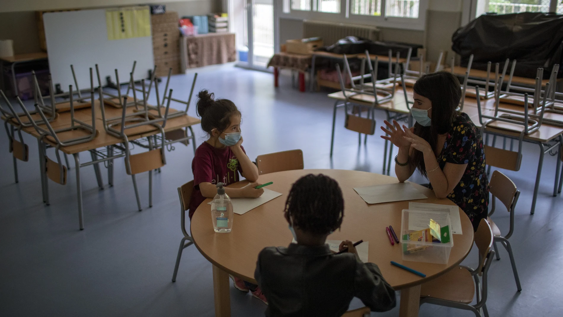Oumou Salam Niang, 6, y Andrea Celeste, 7, se sientan en clase con la profesora Anna Gonzalves, el primer día de reapertura de colegios en Barcelona. (AP Photo/Emilio Morenatti)