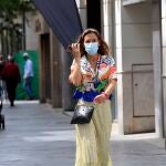 Una mujer, equipada con mascarilla, pasea por una calle de Sevilla