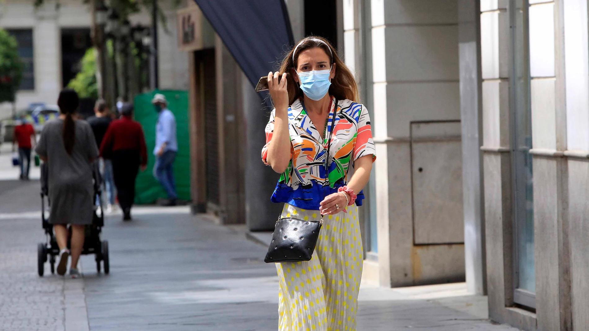 Una mujer, equipada con mascarilla, pasea por una calle de Sevilla