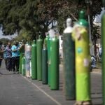 César Garcia descansa sobre un cilindro de oxígeno en una larga fila para rellenarlo en Lima