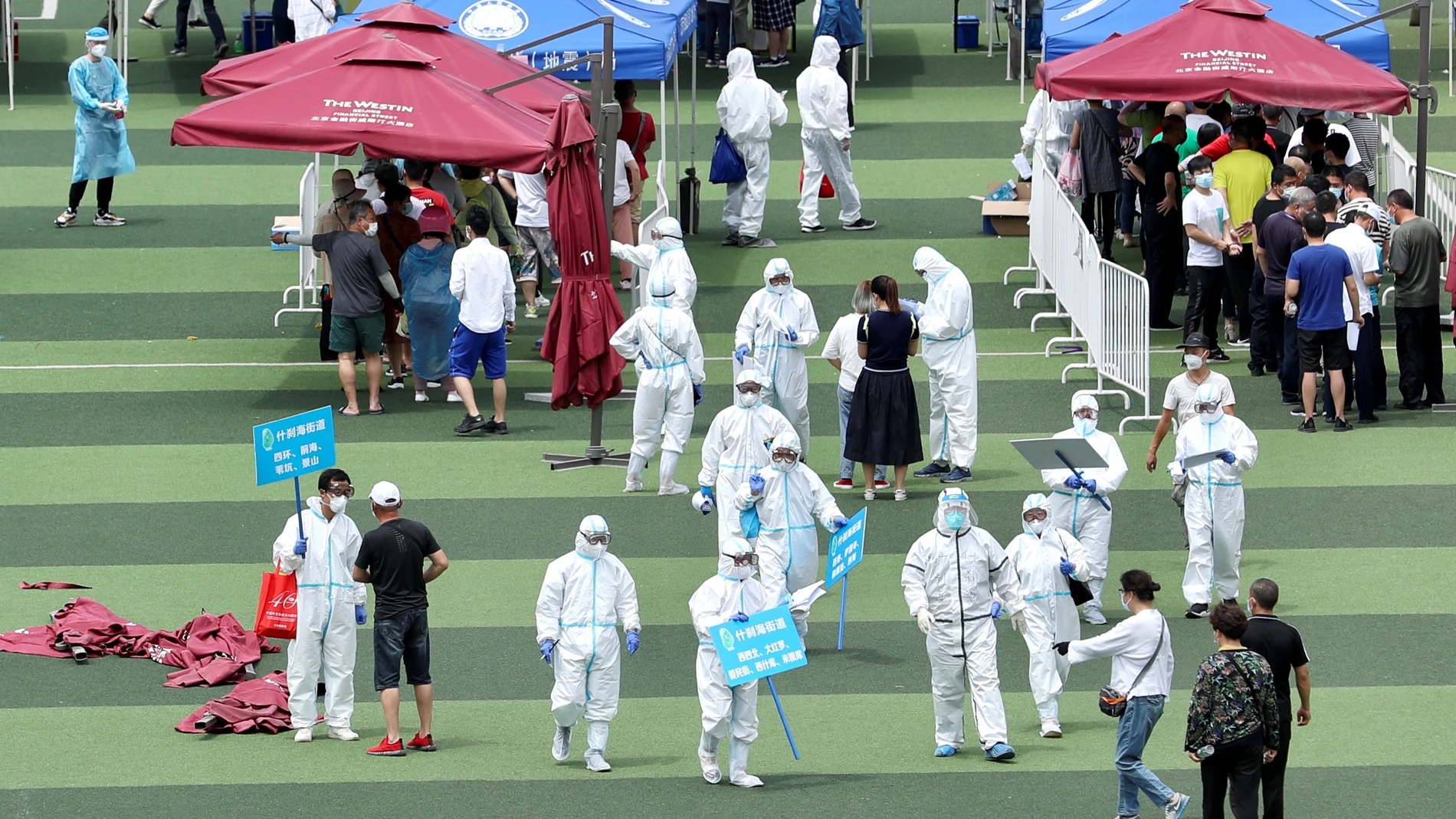 Medical workers help people lining up inside a sports centre for nucleic acid tests in Beijing