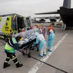 Personal sanitario de la Fuerza Aérea de Chile (FACH) e integrantes del Servicio de Atención Médica de Urgencia SAMU (de naranja) llevan a un avión a un paciente crítico de COVID-19