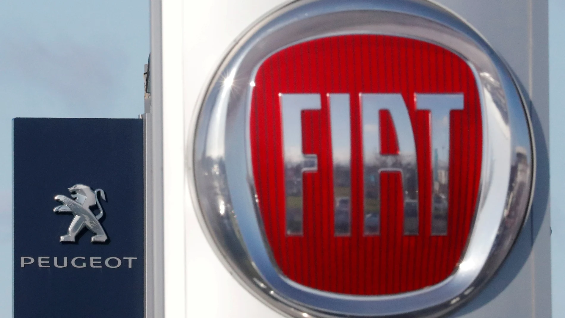 FILE PHOTO: The logos of car manufacturers Fiat and Peugeot are seen in front of dealerships of the companies in Saint-Nazaire