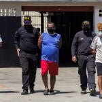 Funcionarios policiales llevan detenidos a Gerardo Enrique Oliveros Laborda (c) y a Yerimi Segundo Machado (d), en la sede de la Policía del Zulia (Venezuela)