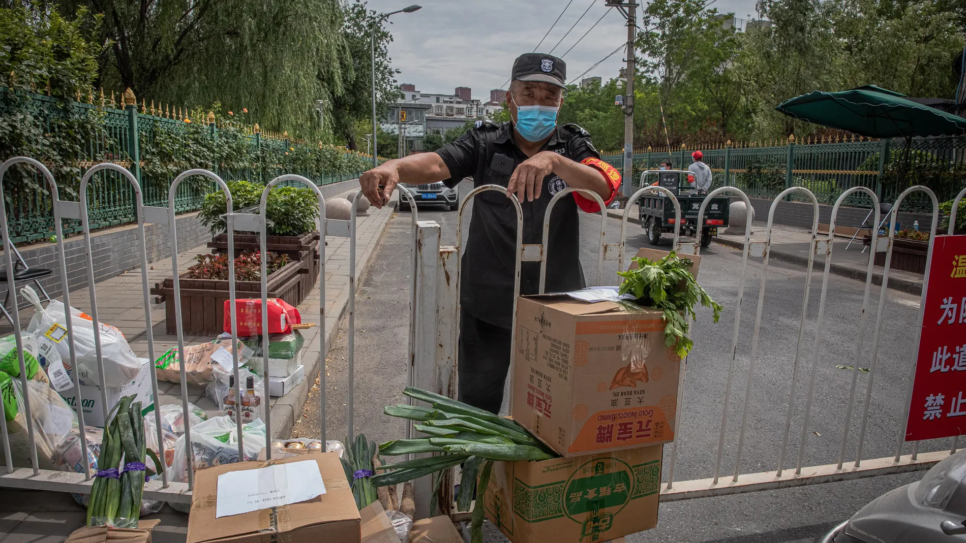 Un vigilante junto a cajas de comida a la entrada de un barrio pequinés sometido a confinamiento