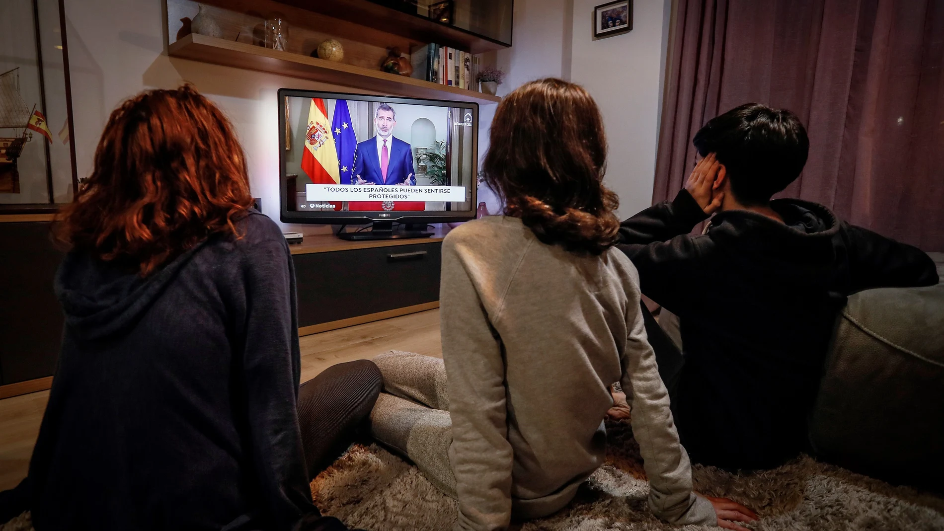 Una familia ve por televisión el mensaje del Rey por la crisis sanitaria al inicio de la pandemia