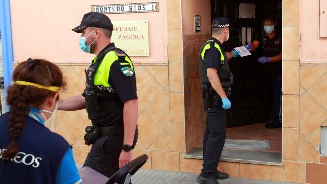 Un policía local entrega una carta certificada urgente al dueño de la pensión Zagora en Algeciras (Cádiz), que se encuentra aislada con una veintena de personas dentro por un brote de coronavirus