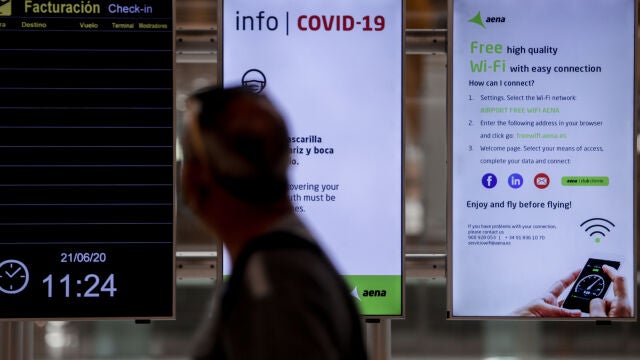 Un hombre pasa junto a unos paneles con información de la Covid-19 en el Aeropuerto de Adolfo Suárez Madrid-Barajas