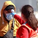 Una miembro de la Cruz Roja toma la temperatura a uno de los cinco magrebíes rescatados por la embarcación de Salvamento Marítimo "Denebola" cuando atravesaban el Estrecho a bordo de dos kayaks el pasado mes de junio