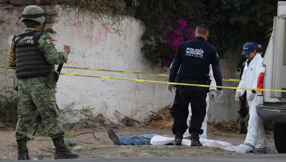 Integrantes de la Guardia Nacional, Policía Estatal y Servicios Periciales revisan el cuerpo de un hombre este domingo las calles de la ciudad de Apaseo El Alto en el estado de Guanajuato (México)