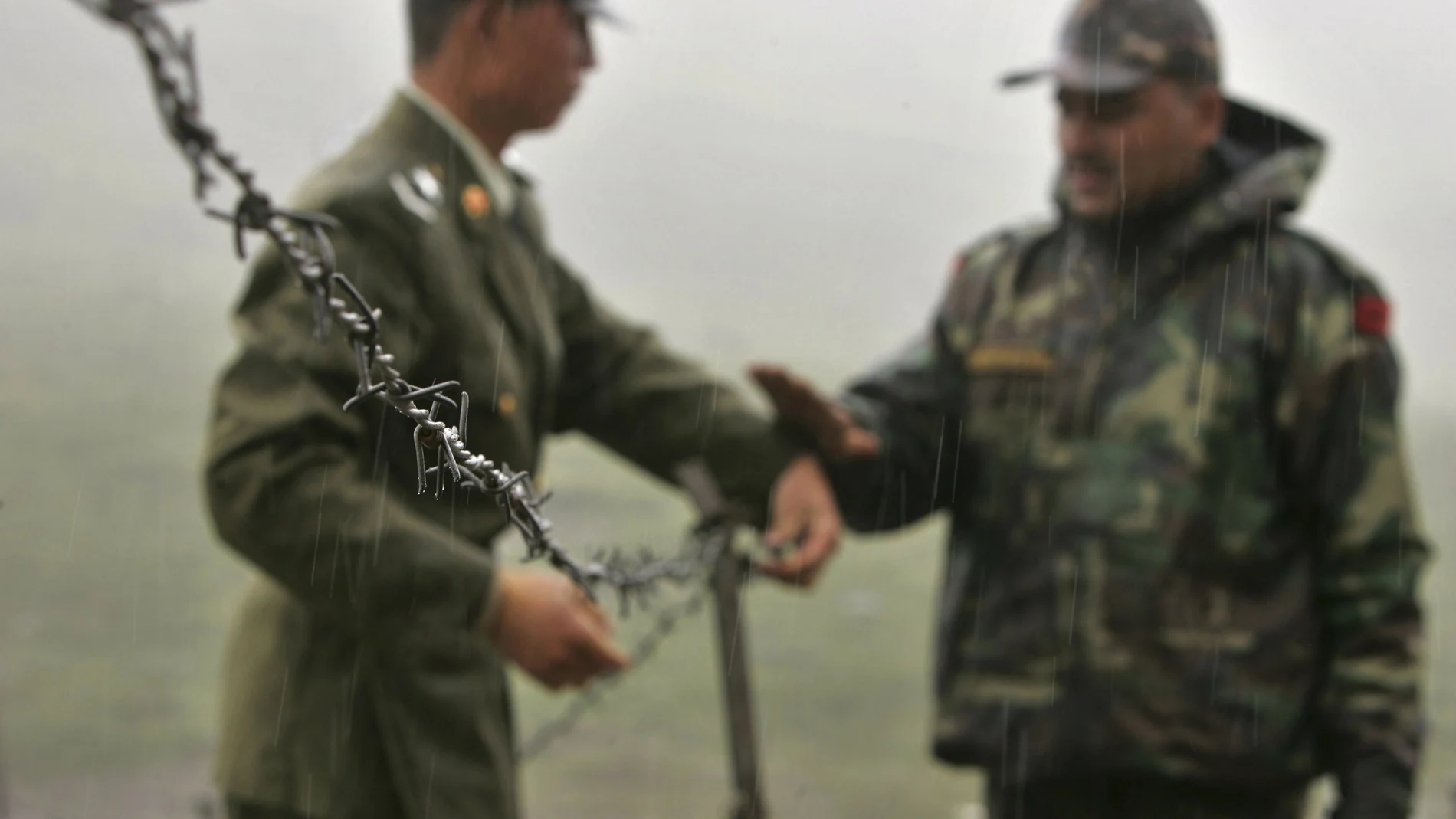 Foto de archivo en la que se ve a un soldado chino (a la izquierda) y a otro soldado indio colocando una concertina en la frontera en Sikkim