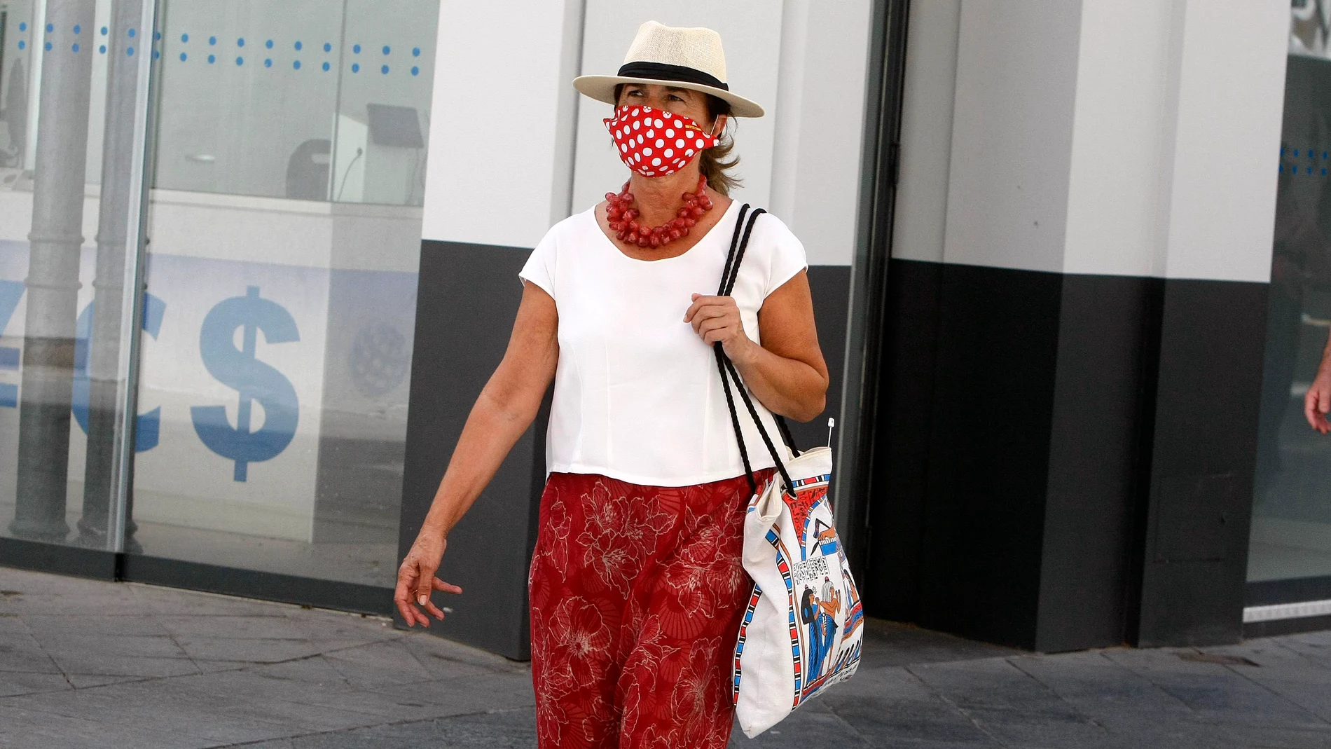 Una mujer pasea con una mascarilla personalizada por el centro de Sevilla