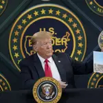 El presidente Donald Trump muestra una foto del muro que quiere levantar entre México y EE UU en un acto público en Yuma (Arizona)