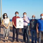 El delegado territorial de Turismo, José Luis Delgado y el alcalde del municipio, Manuel Cortes, junto a otros representantes del Consistorio y la responsable de Protección Civil, presentan el distintivo en una playa de Adra