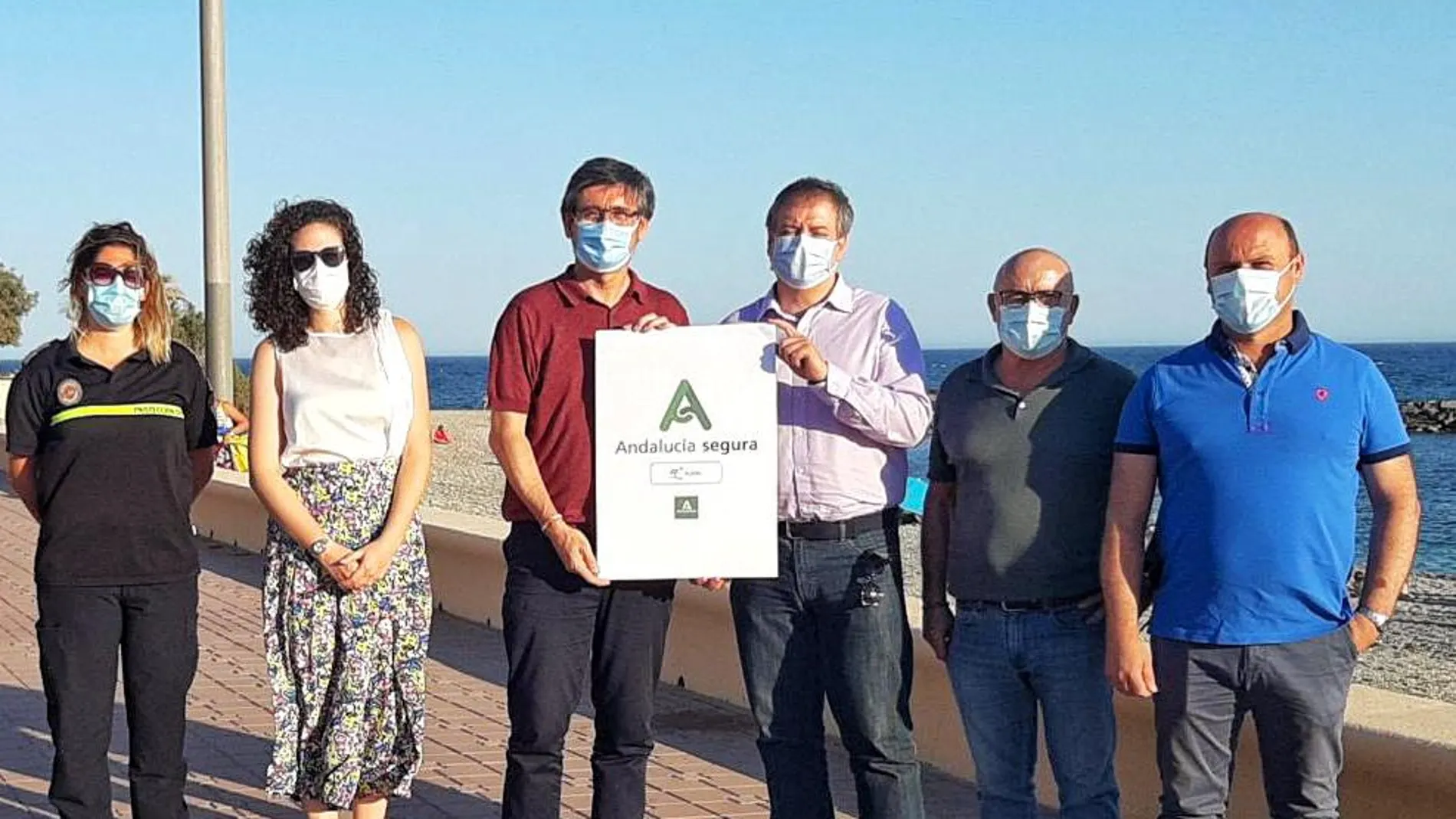 El delegado territorial de Turismo, José Luis Delgado y el alcalde del municipio, Manuel Cortes, junto a otros representantes del Consistorio y la responsable de Protección Civil, presentan el distintivo en una playa de Adra