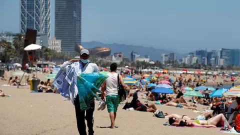 Un vendedor ambulante ofrece sus productos en la playa de Barcelona