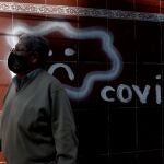 A man wearing a mask to curb the spread of the new coronavirus walks past COVID-19 graffiti, in La Paz, Bolivia, Wednesday, June 24, 2020. (AP Photo/Juan Karita)