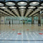 Círculos rojos en el suelo indican la distancia de seguridad que deben mantener los pasajeros para controlar la propagación del coronavirus en el Aeropuerto Madrid-Barajas Adolfo Suárez
