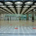 Círculos rojos en el suelo indican la distancia de seguridad que deben mantener los pasajeros para controlar la propagación del coronavirus en el Aeropuerto Madrid-Barajas Adolfo Suárez